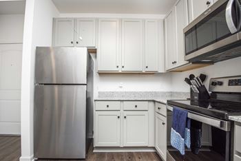 A kitchen with a stainless steel refrigerator and white cabinets.